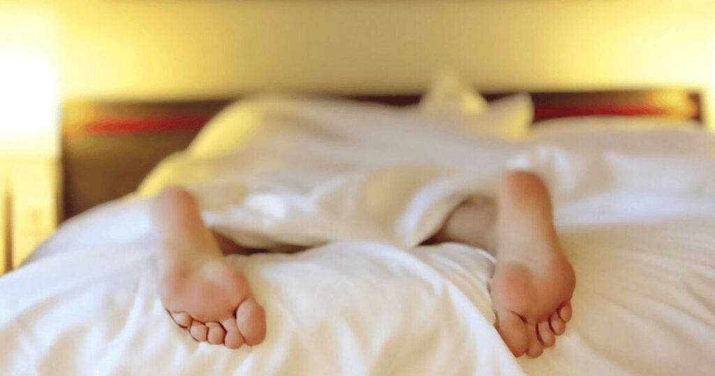 child in sleeping in bed with bottom of feet showing
